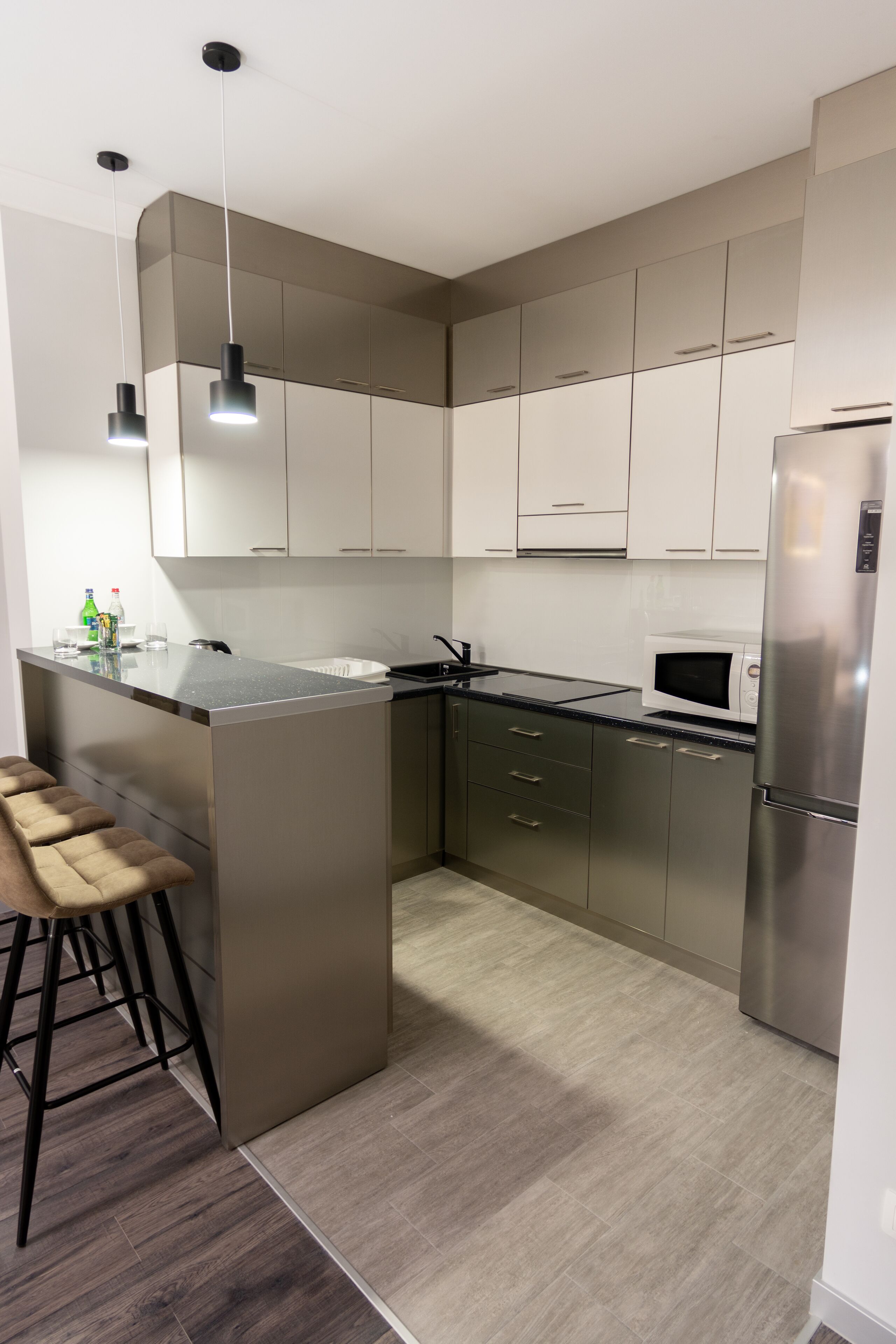 Una cocina moderna con una isla central, electrodomésticos de acero inoxidable y taburetes de bar.