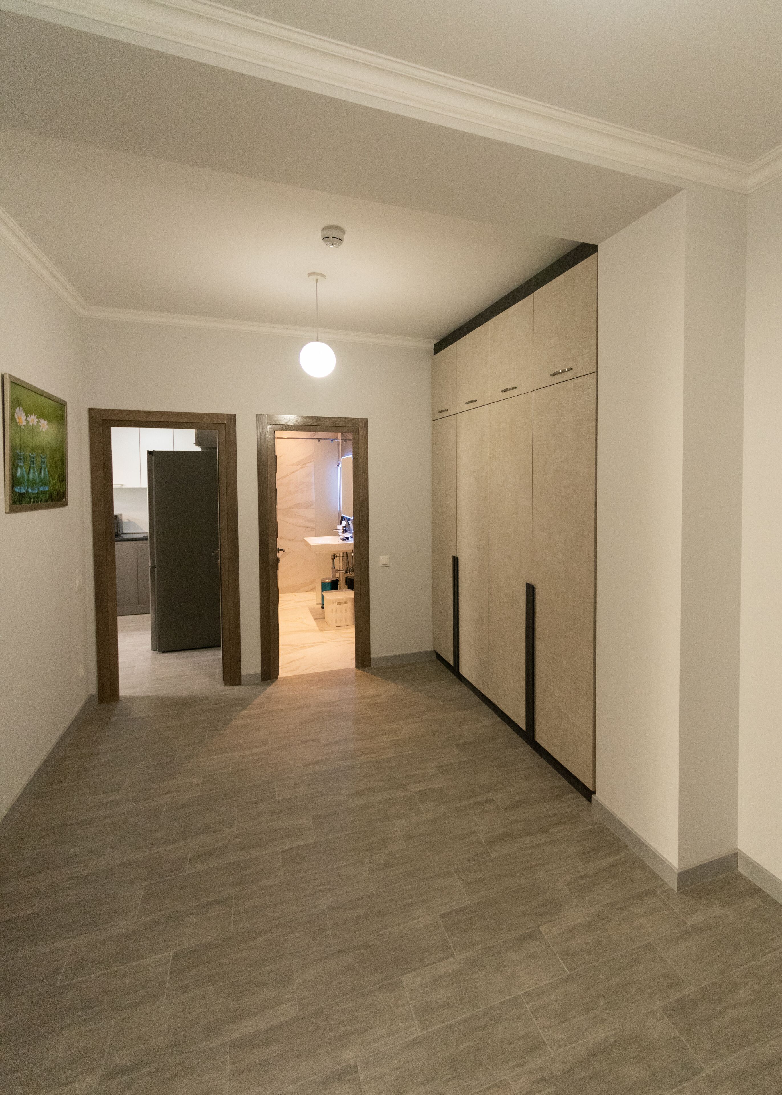 A hallway with a wooden floor, a wardrobe, and a door leading to a bathroom.