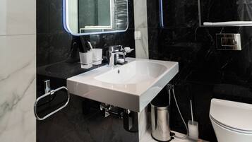Un baño moderno con un espejo grande, un lavamanos blanco y un inodoro.