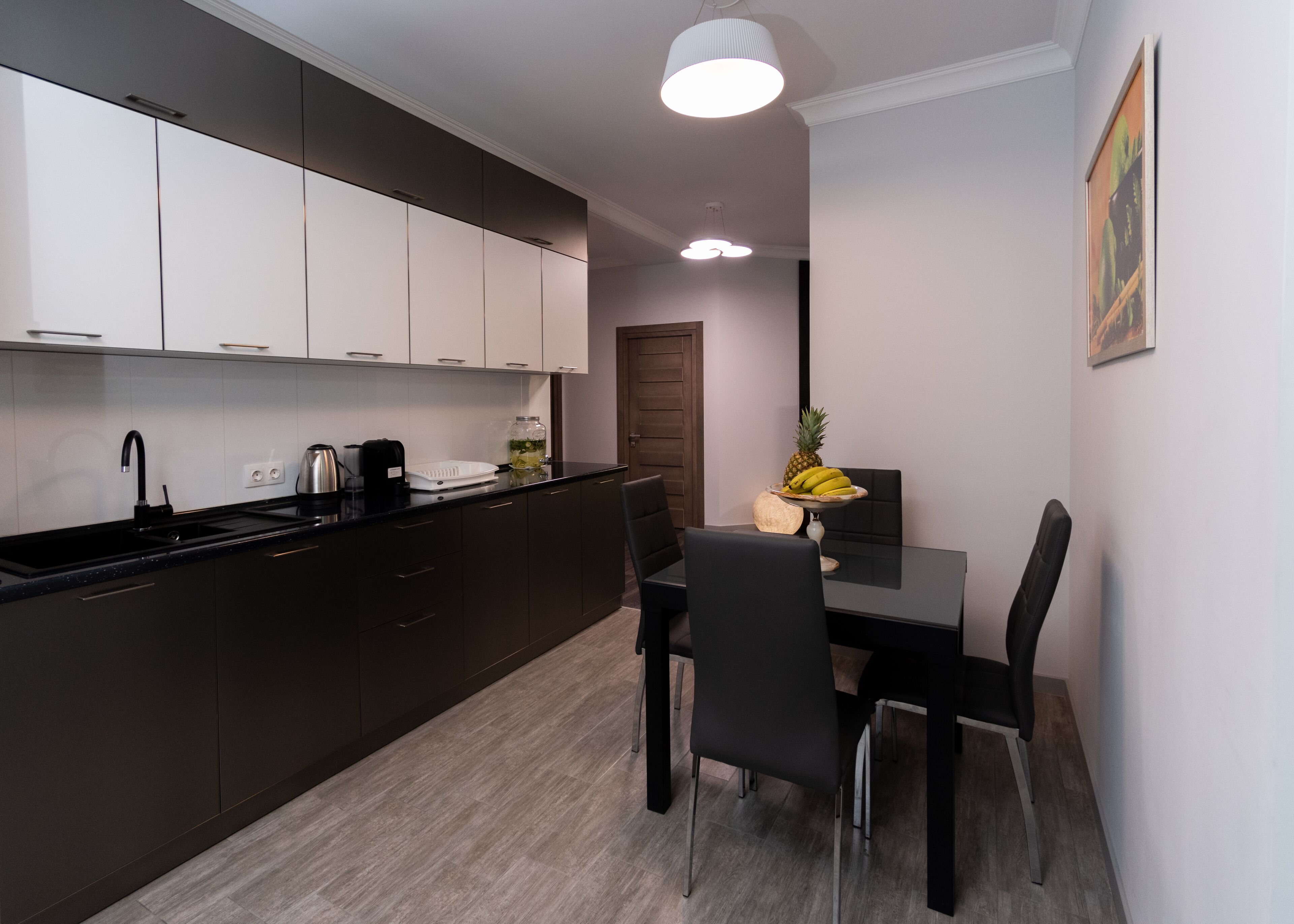 A modern kitchen with dark cabinets, a black countertop, and a dining area with a table and chairs.
