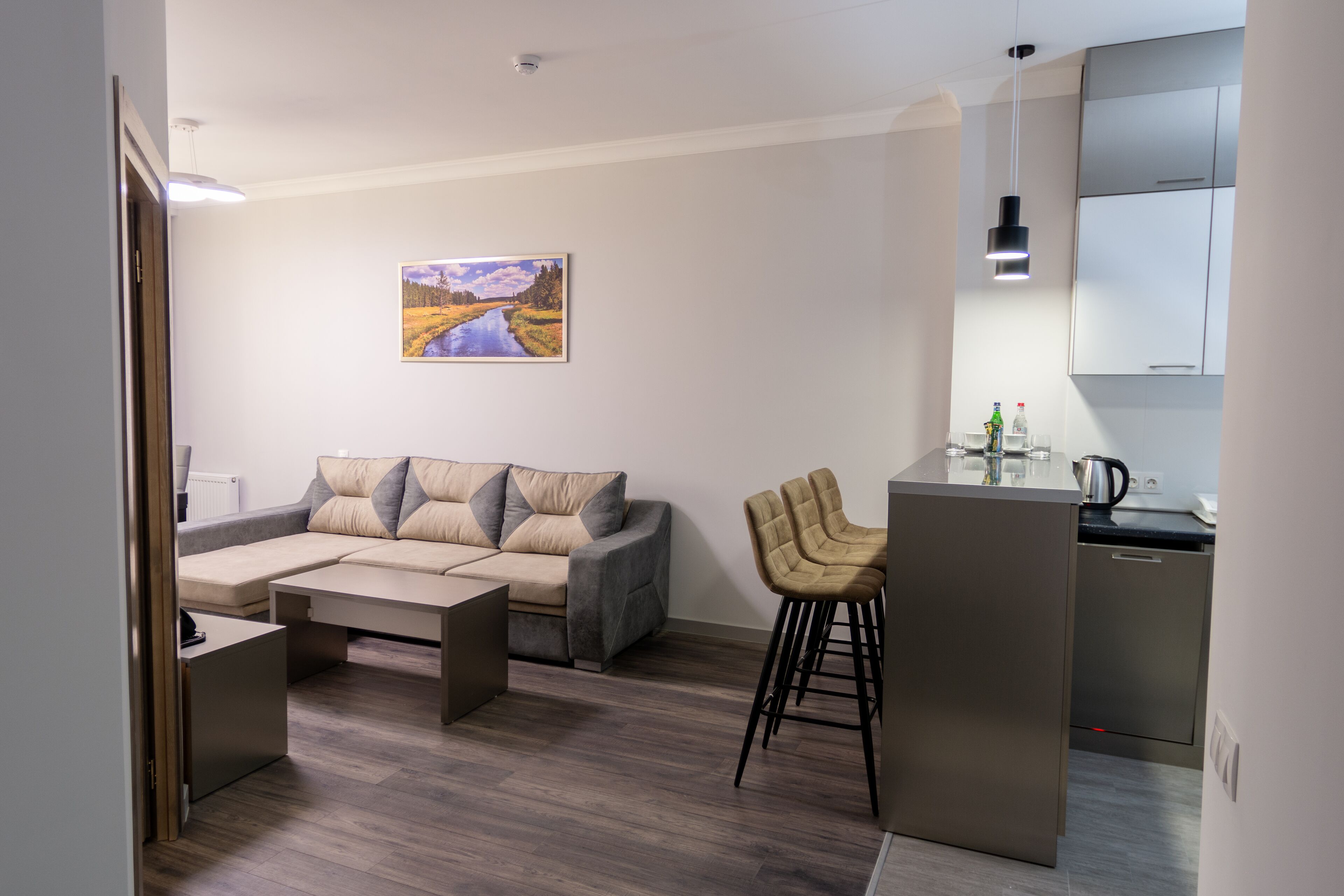 A modern living room with a sofa, a coffee table, and a kitchen area with a bar stool.