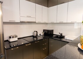 Een moderne keuken met roestvrijstalen apparatuur, een zwart aanrecht en witte kasten.