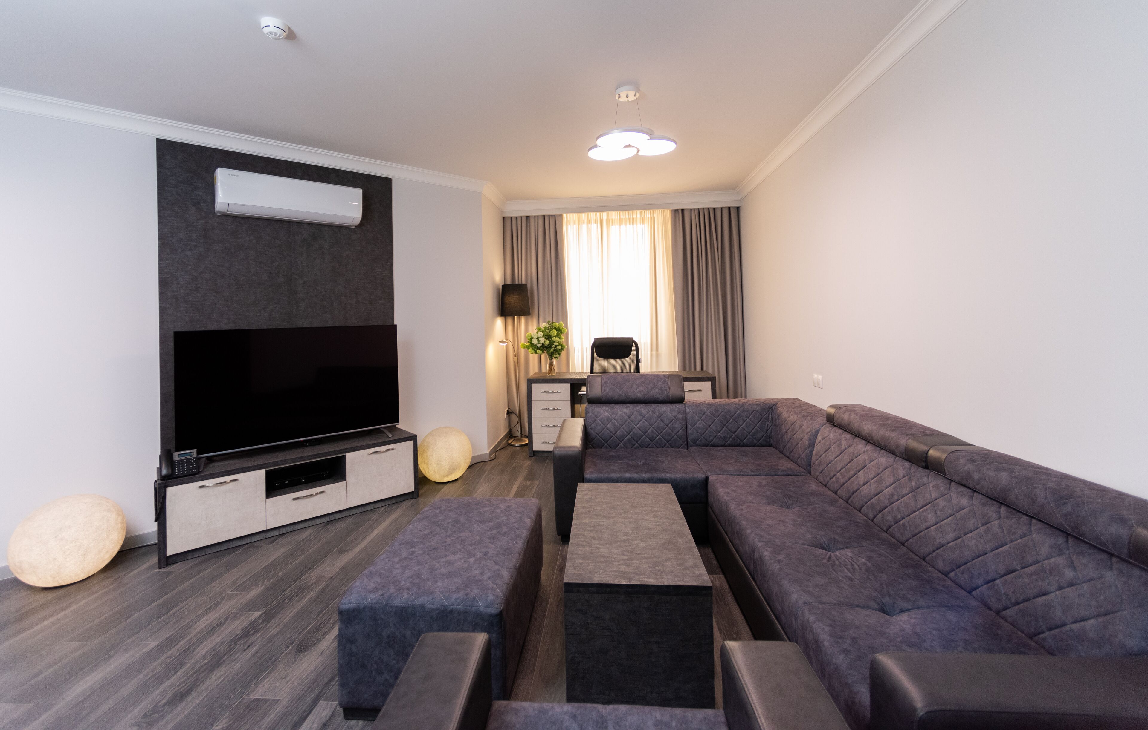 Una sala de estar moderna con un televisor de pantalla plana grande, un sofá modular, una mesa de centro y una mesita auxiliar.