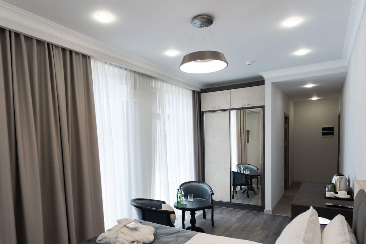 A hotel room with a large bed, a desk, a chair, and a mirror.