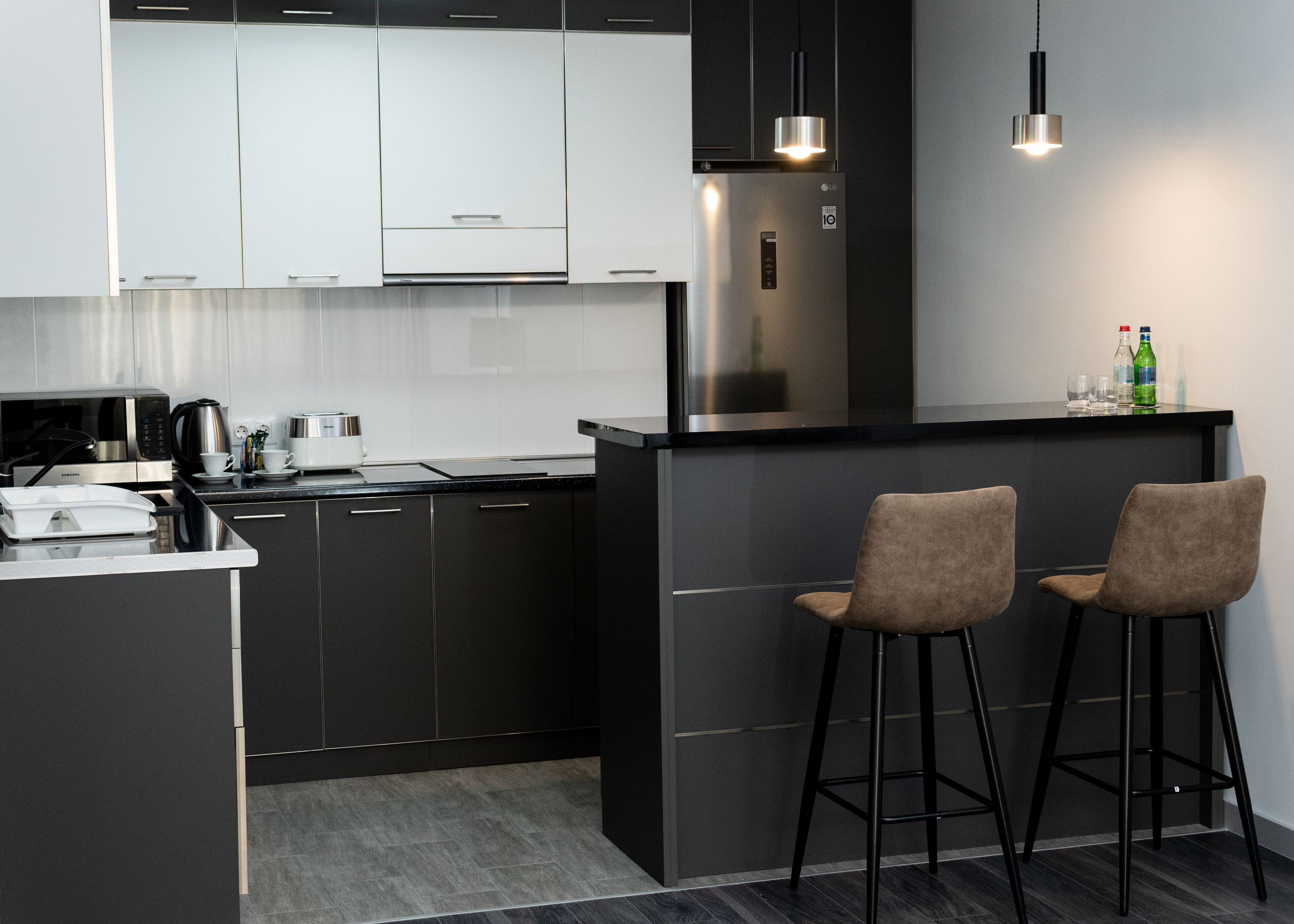 Une cuisine moderne dotée d’un îlot central intégré, d’appareils électroménagers en acier inoxydable et de tabourets de bar.