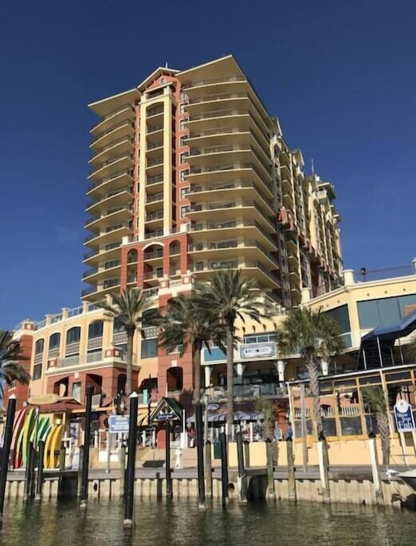 Un hôtel à plusieurs étages, doté de balcons, situé près du bord de l’eau.