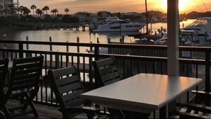 En restaurang vid vattnet med uteservering, med utsikt över en småbåtshamn med lyxbåtar.