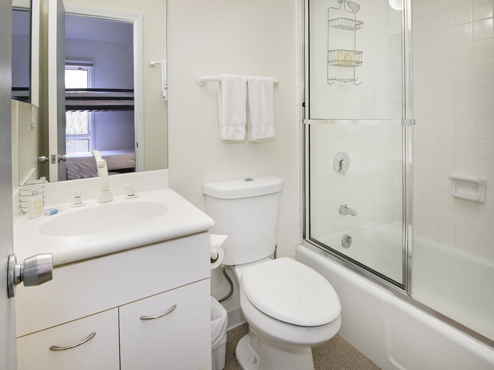Un baño con lavamanos blanco, inodoro y cabina de ducha de vidrio.