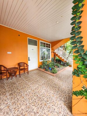 Una habitación con piso de baldosas, una puerta blanca, una ventana y una escalera que lleva a un balcón.