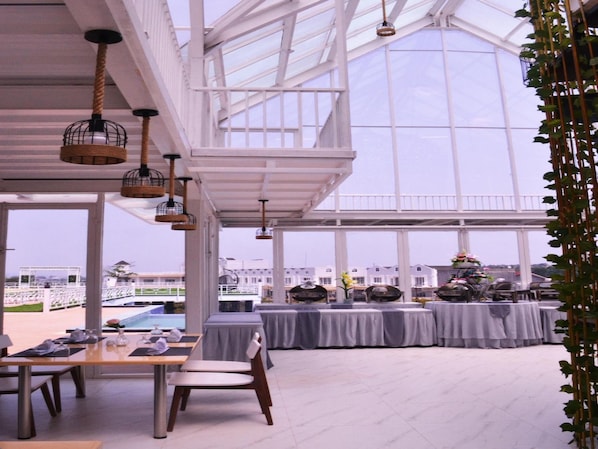 A spacious indoor area with tables and chairs, large windows, and hanging light fixtures. - Chevilly Resort And Camp (Ciawi)