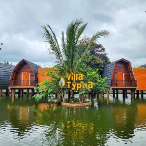 Alojamiento sobre el agua con estructuras de madera y un cartel central que indica Villa Typha.