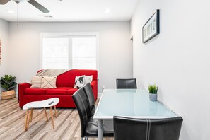 A modern living room with a red sofa, a glass table, and black chairs.
