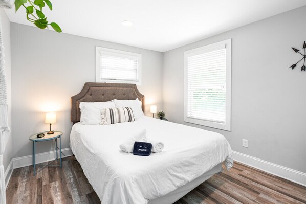 Relax in this serene bedroom with a large bed, bedside table, and decorative wall piece.