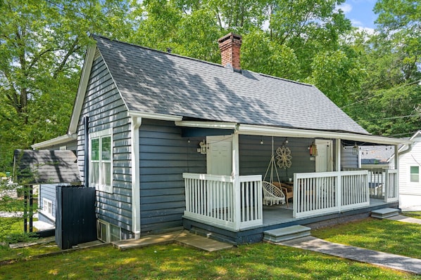 A single-story house with a porch, a chimney, and a small deck.