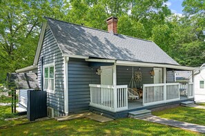 Traditional home with a charming front porch and lush green surroundings.
