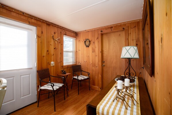 A room with wooden walls, a dining table with candles, chairs, and a lamp.