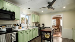 A kitchen with green cabinets, a black microwave, and a ceiling fan. - The Lodge House - Centrally Located Cheerful 5BR - Minutes to Gore! (North Creek)