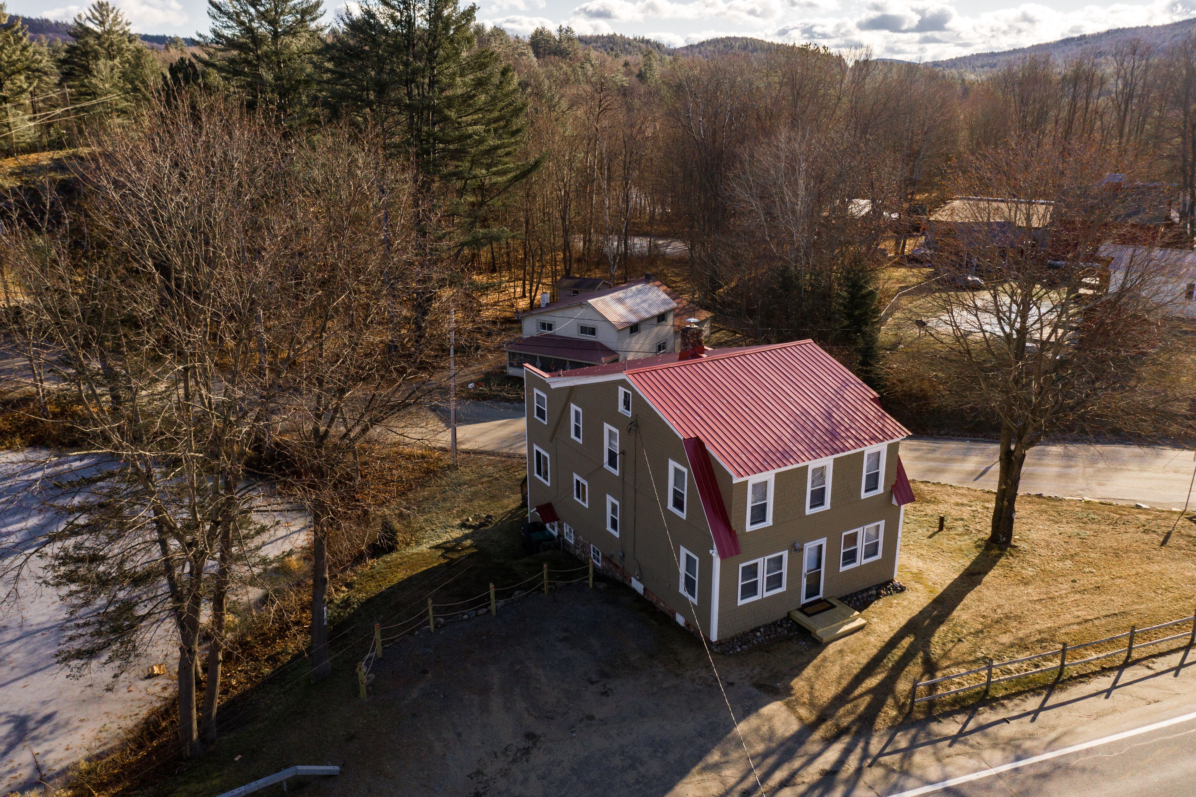 A multi-story building with a red roof, surrounded by trees and a snow-covered landscape.