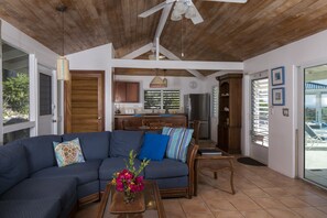 A spacious living area with a sectional sofa, wooden ceiling, and a view of the kitchen and outdoor space. - Blue Agave Villa- Dazzling Sunsets, Amazing Views, Pool, Generator A/C in Br's (Cruz Bay)