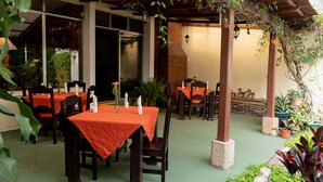 An outdoor dining area with tables and chairs, covered by a wooden pergola, and surrounded by potted plants. - Hostal Donde Regina (Guatemala City)