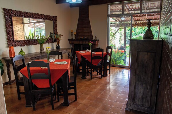 A dining area with tables, chairs, a fireplace, and a large mirror.