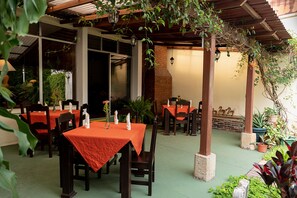 An outdoor dining area with tables and chairs, covered by a wooden pergola, and surrounded by potted plants. - Hostal Donde Regina (Guatemala City)