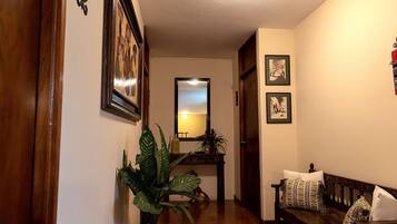 A hallway with a wooden bench, a potted plant, and framed pictures on the walls.