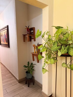 A hallway with a wooden chair, a small table, and a potted plant. - Hostal Donde Regina (Guatemala City)