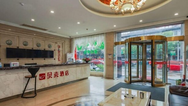 Un vestíbulo de hotel con una recepción, una zona de estar y una puerta giratoria.