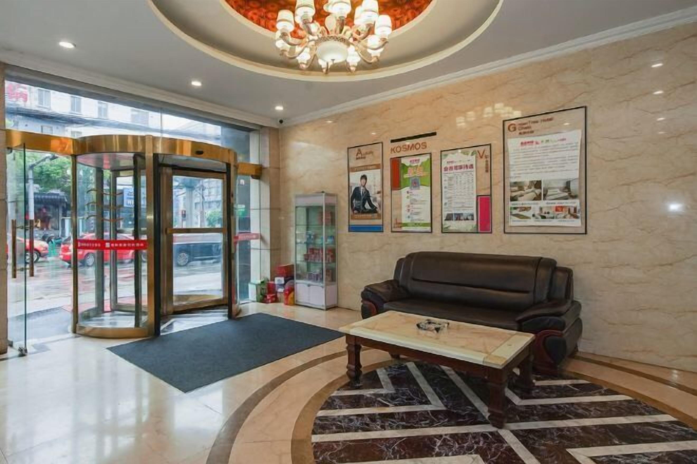A lobby with a revolving door, a black leather sofa, a coffee table, and a chandelier.