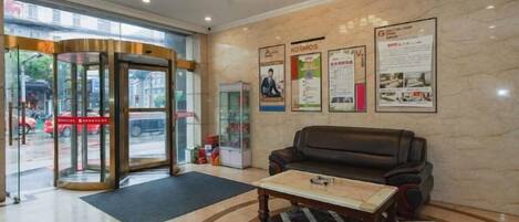 A lobby with a revolving door, a black leather sofa, a coffee table, and a chandelier.