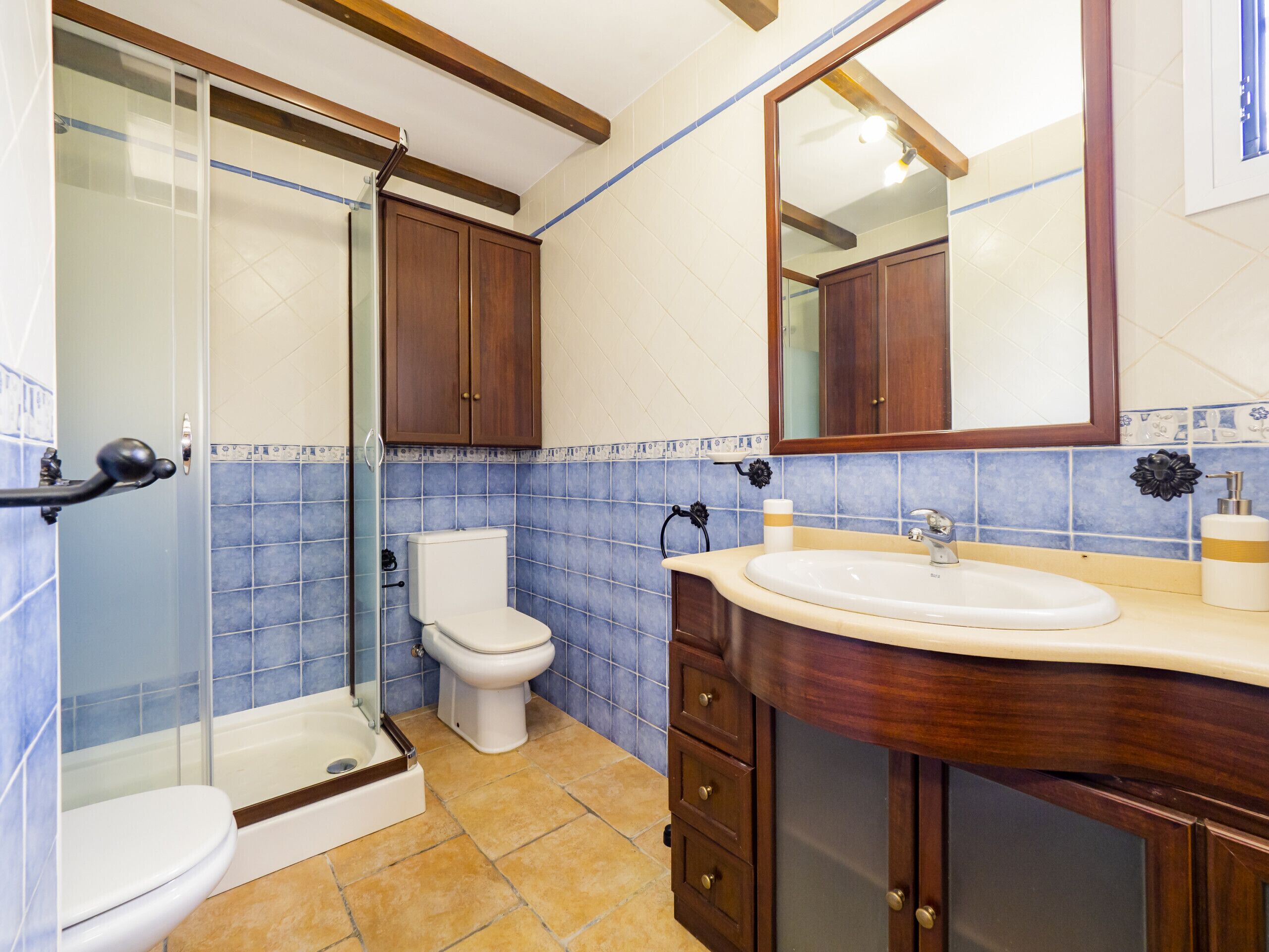 Ein Badezimmer mit Duschkabine, Toilette, Waschbecken mit Unterschrank und Spiegel.