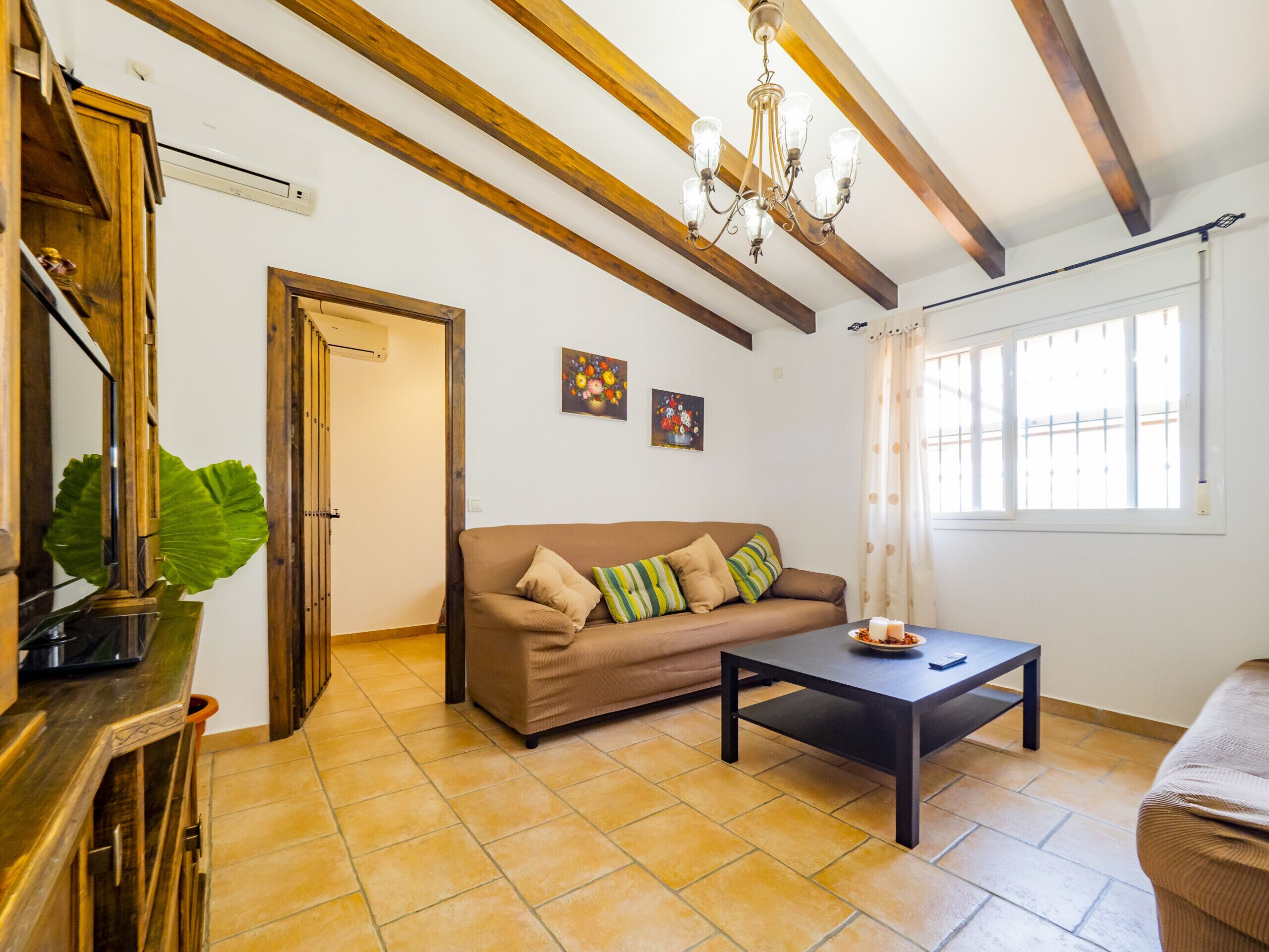 Una sala de estar con un sofá marrón, una mesa de centro negra y un techo de madera con vigas a la vista.