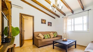 Una sala de estar con un sofá marrón, una mesa de centro negra y un techo de madera con vigas a la vista.