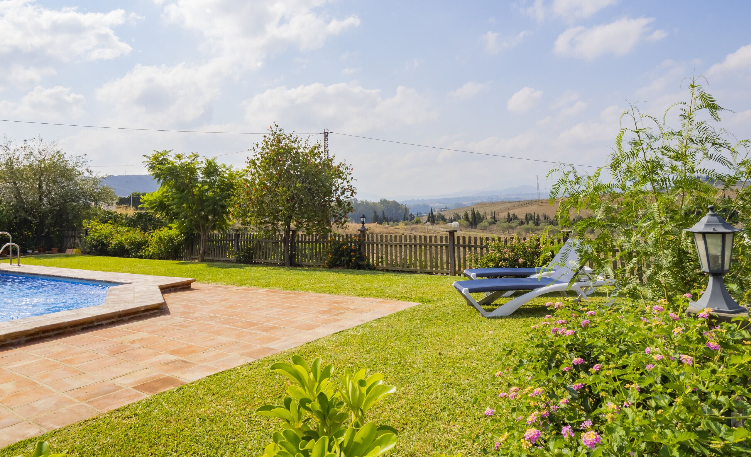 Un patio trasero con piscina, cercado de madera y césped.