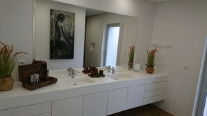 Un bagno moderno con un grande specchio, due lavandini e piante ornamentali.