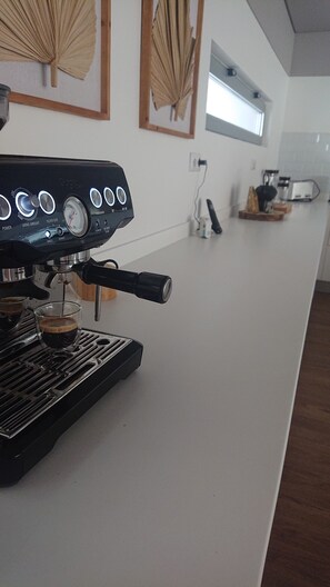 A coffee machine with a digital display, a coffee cup, and a kitchen counter. - Lux Private Villa  (Rabo de Peixe)