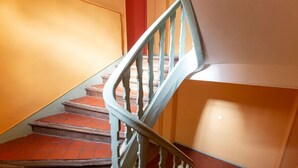 Eine Treppe mit Holzgeländer und roten Fliesenstufen, die zu einer höheren Etage führt.