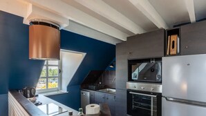 Eine moderne Küche mit Einbauofen, Edelstahlgeräten und einem großen Fenster für natürliches Licht.