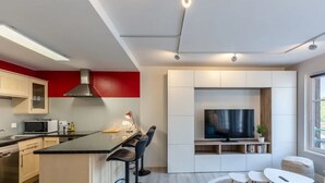 Ett modernt kök med en köksö i mitten, en inbyggd mikrovågsugn och en stor tv-skärm.