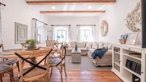 A living room with a wooden dining table, wicker chairs, a sofa, and a bookshelf. - House Bella (Bohinjska Bela)