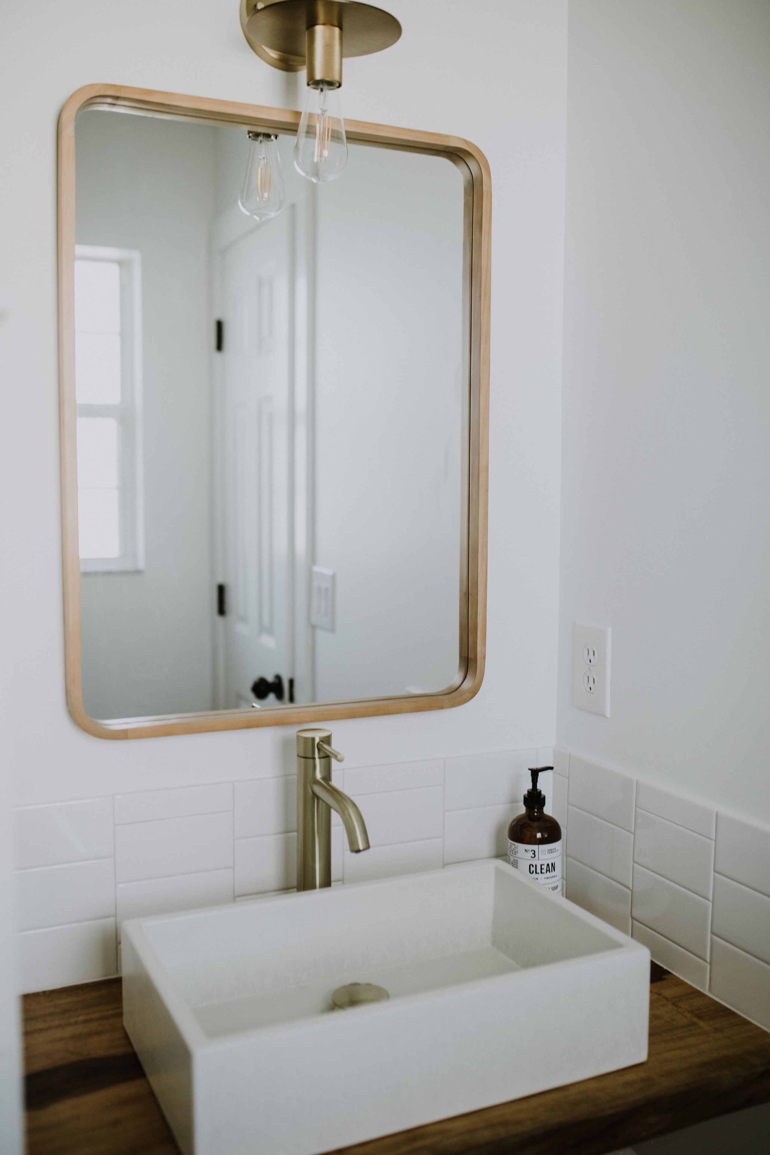 A bathroom with a rectangular mirror, a white sink, and a wooden countertop.