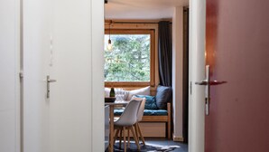 Un pasillo estrecho que conduce a una habitación con una cama, una mesa y un ventanal.