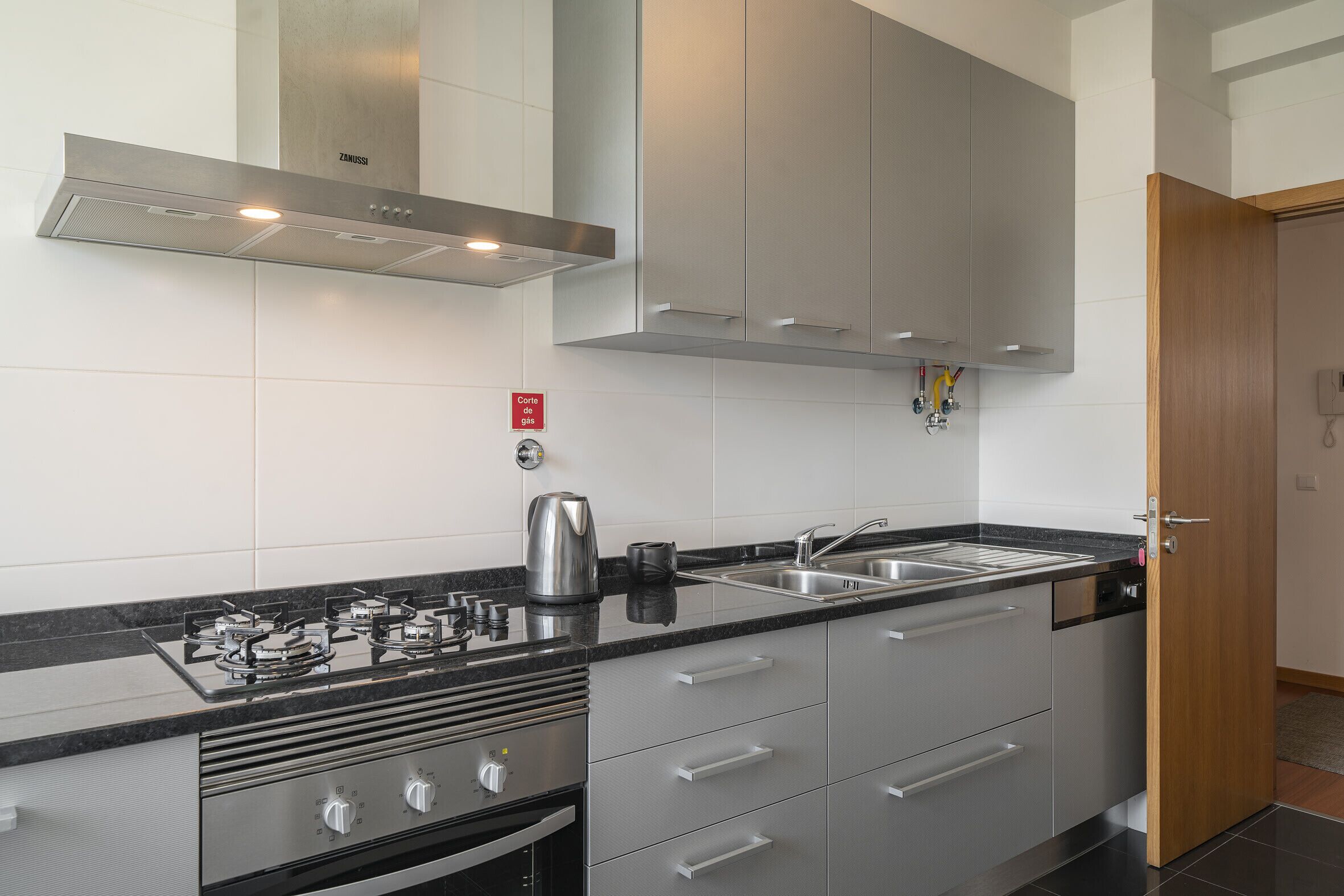 A modern kitchen with stainless steel appliances, a built-in oven, and a double sink.