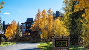 A sign for Woods Manor with a clear view of the surrounding autumnal trees and a road leading to the property. - Remodeled Nice Top-Floor Condo. Hot Tub. Fireplace (Breckenridge)