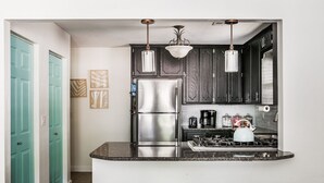 A kitchen with dark wood cabinets, a stainless steel refrigerator, a gas stove, and three light blue stools. - Cozy 3 bdrm w/pool & hot tub!! (Oklahoma City)