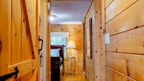 Un corridoio in legno con un letto, una lampada e una luce a soffitto.