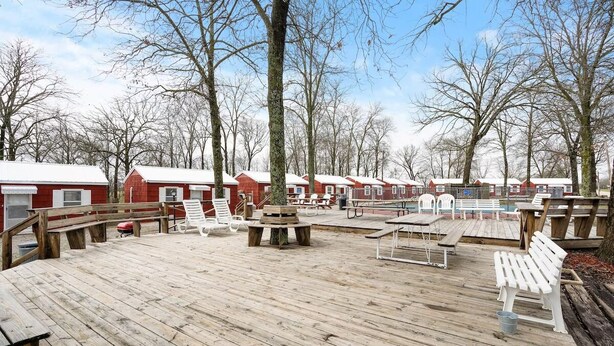 Une terrasse en bois avec des sièges extérieurs, entourée de bâtiments rouges aux contours blancs.