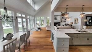 Une cuisine spacieuse dotée d’un grand îlot central, d’un plancher en bois et offrant une vue sur l’extérieur.