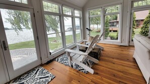 Une pièce spacieuse avec de grandes fenêtres, un plancher en bois et une chaise blanche.